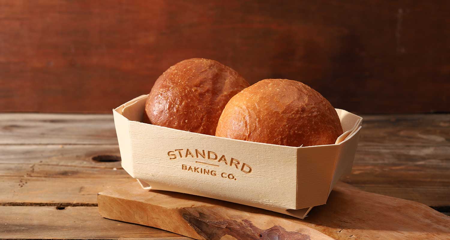 Two brioche rolls in a Standard Baking Company basket
